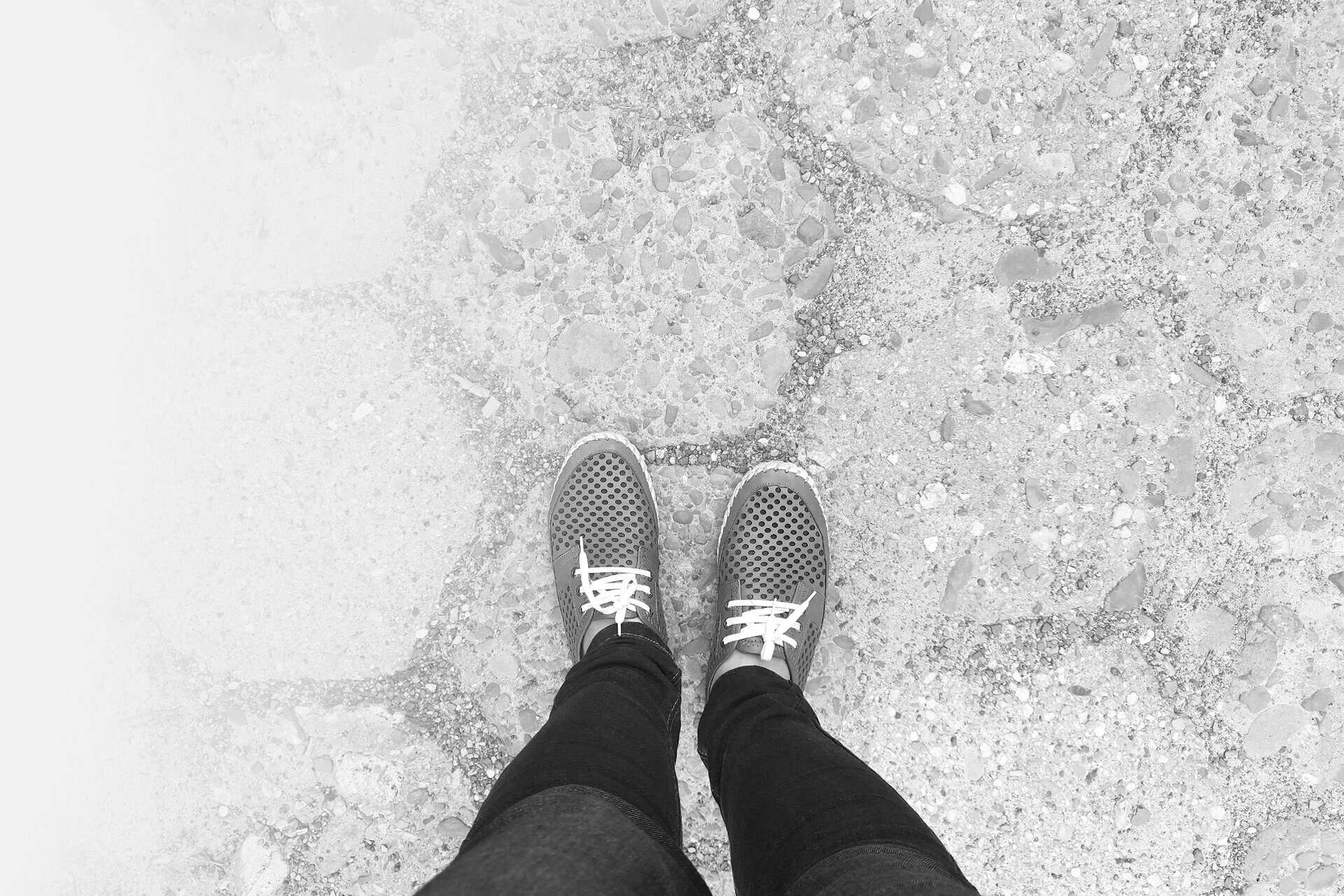 Feet In Moccasins Stand On Sidewalk. View From Above.